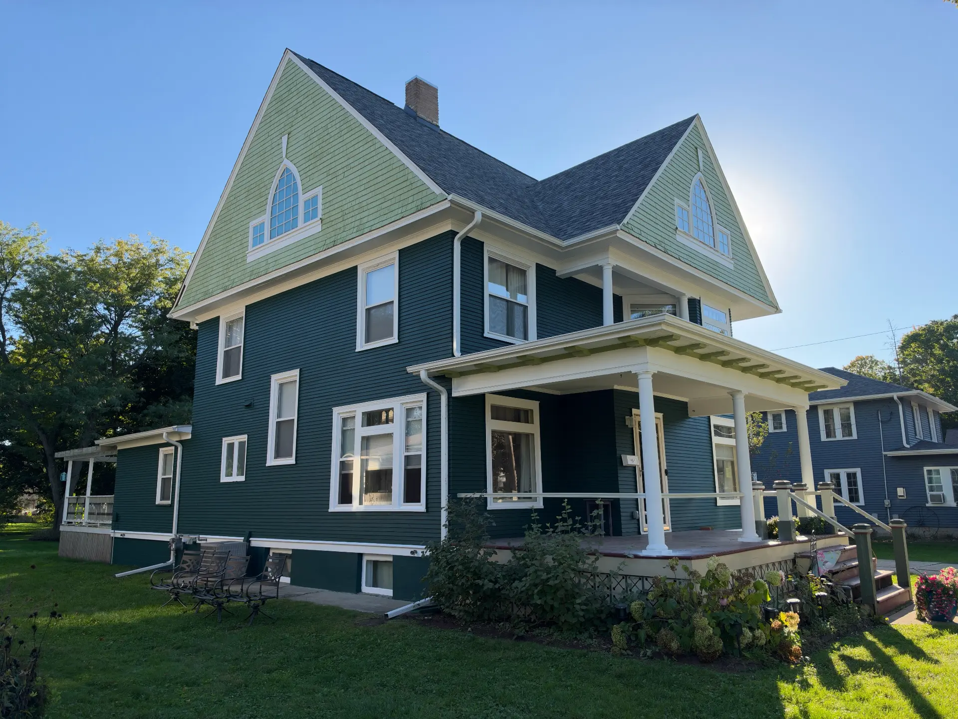 Historic home with fresh dark teal siding, mint gable shingles, and white trim in Evansville, Wisconsin