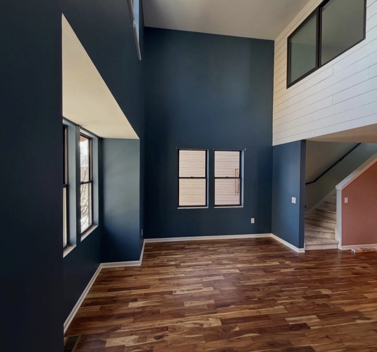 Two story interior with dark navy accent wall painting